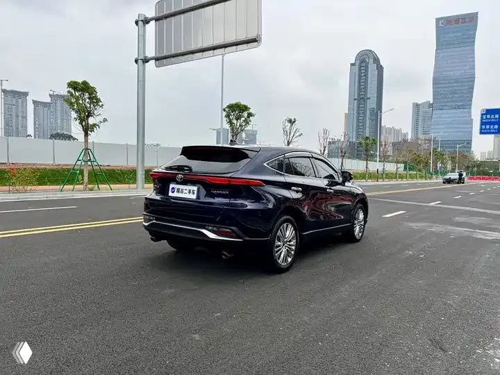 Вид на заднюю часть Toyota Harrier 2022: фара, багажная дверь и наружные элементы, автомобиль на фоне городской застройки и дороги.