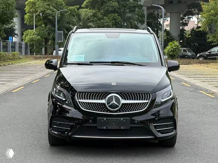 Фронтальный вид чёрного Mercedes‑Benz Vito 2022 года, прямой ракурс, номерная рамка без номера, улица и деревья на заднем плане.