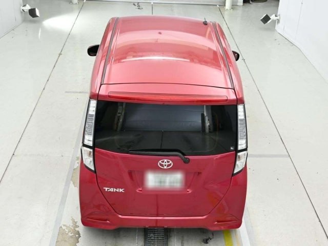 Вид сверху сзади красного Toyota Tank 2018 в аукционной фотостудии; видна крыша, багажная дверь и общий вид задней части кузова.