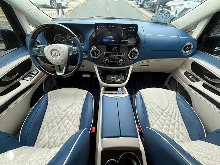 Салон Mercedes‑Benz Vito: панель приборов, руль и центральный дисплей; два передних сиденья в бело‑синей комбинированной обивке.