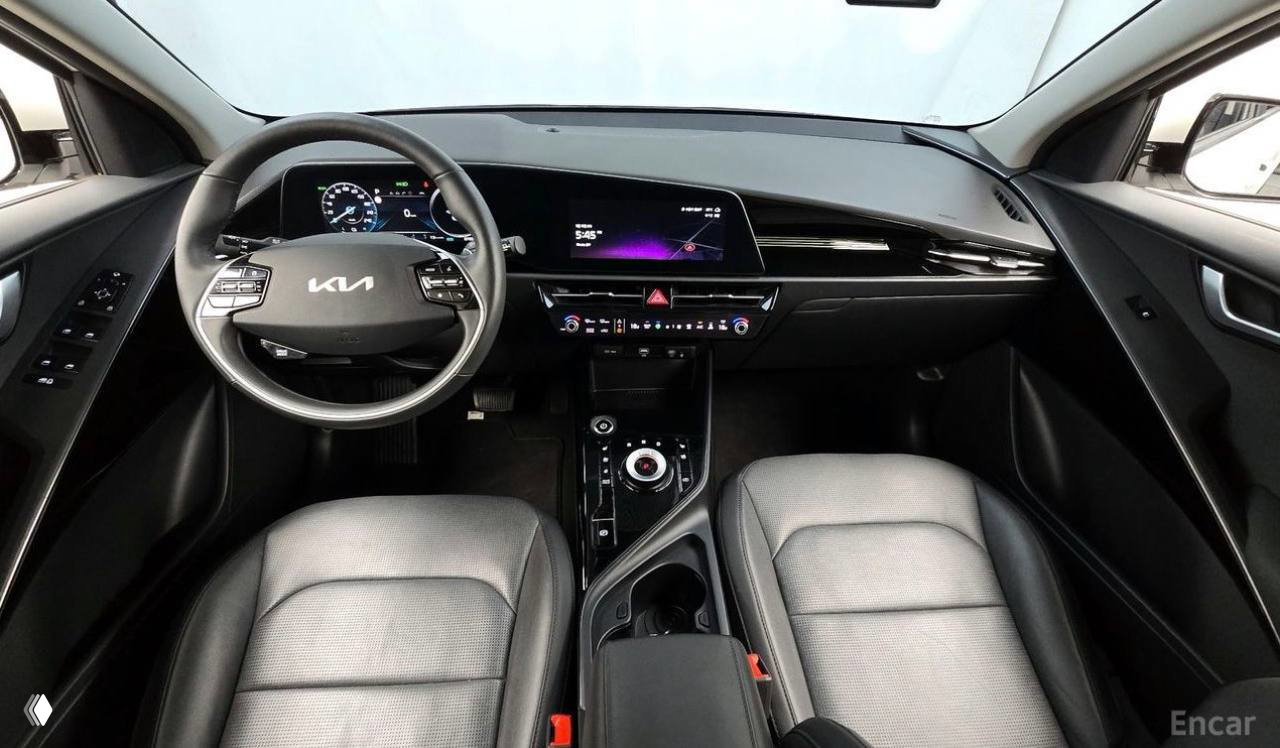Салон Kia Niro — панорамный вид водительского места: руль с логотипом KIA, цифровая приборная панель и мультимедиа экран в интерьере.