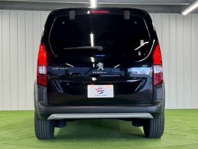 Задняя часть черного Peugeot Rifter 2023 в автосалоне: вид на багажник, фонарь и эмблему Peugeot на крышке багажника