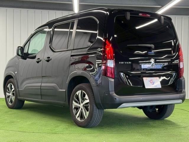 Уголовой вид на заднюю и боковую часть черного Peugeot Rifter 2023: дверной профиль, задние фонари и колёса, общий силуэт автомобиля