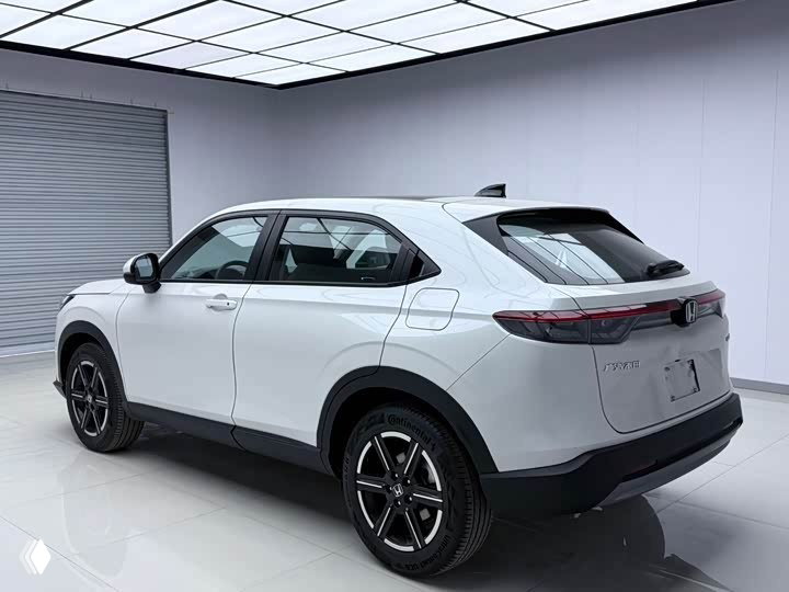 Белый Honda Vezel 2023, вид сзади и сбоку в студийном освещении, показаны фары, багажник и общие пропорции кузова.