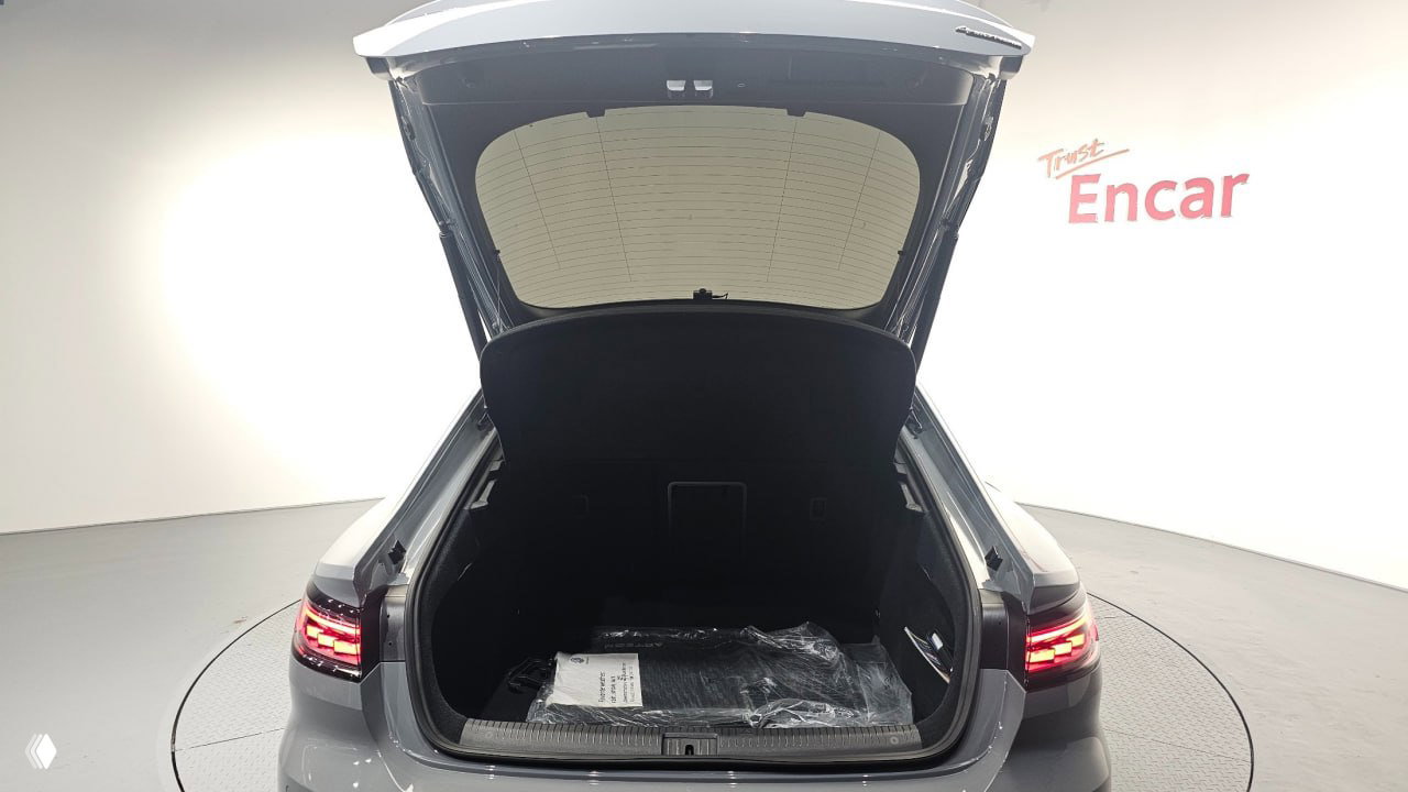 Открытый багажник Volkswagen Arteon 2022 в шоуруме Encar; видна внутренняя обшивка, порог багажника и упакованные аксессуары внутри ниши.