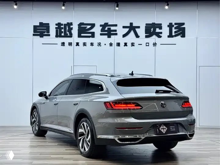Задняя часть серого Volkswagen Arteon 2022 в выставочном зале: вид на фонари, багажник и линии кузова на нейтральном белом фоне шоурума.