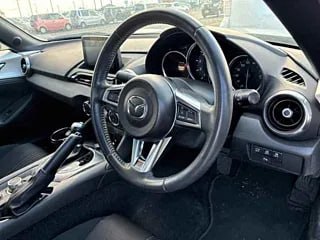 Интерьер Mazda Roadster: руль, приборная панель и центральная консоль с чёткой панелью управления и кожаной отделкой в салоне автомобиля.