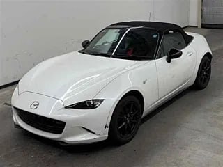 Mazda Roadster белого цвета вид сверху и в три четверти, хорошо видны линии кузова, складной чёрный верх и общий внешний вид машины.