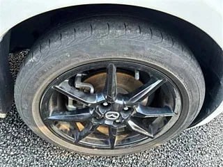 Колесо и легкосплавный диск Mazda Roadster с плотно накачанной шиной; вид сбоку на колесную арку и дорожную резину автомобиля.