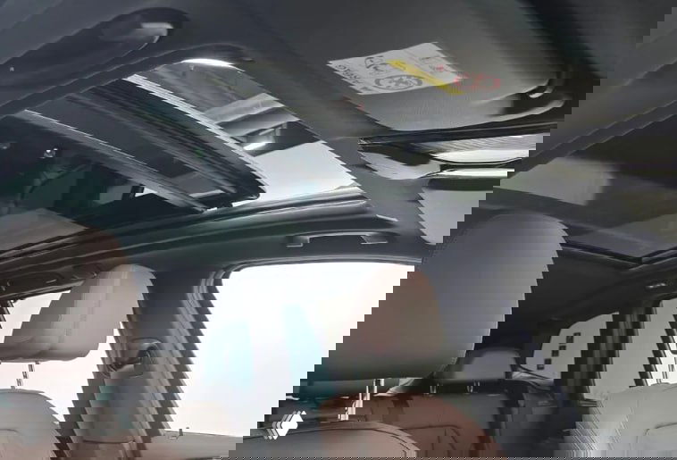 Панорамный люк в BMW X3 M Sport, вид вверх из салона — открытая стеклянная крыша и передние подголовники на фоне белого потолка.