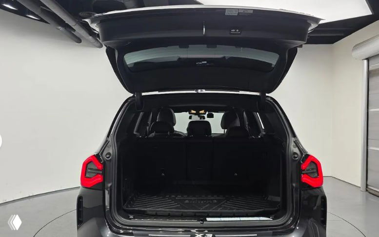 Открытый багажник BMW X3 M Sport 2023 года: просторный грузовой отсек с резиновым ковриком и видом на задние сиденья.