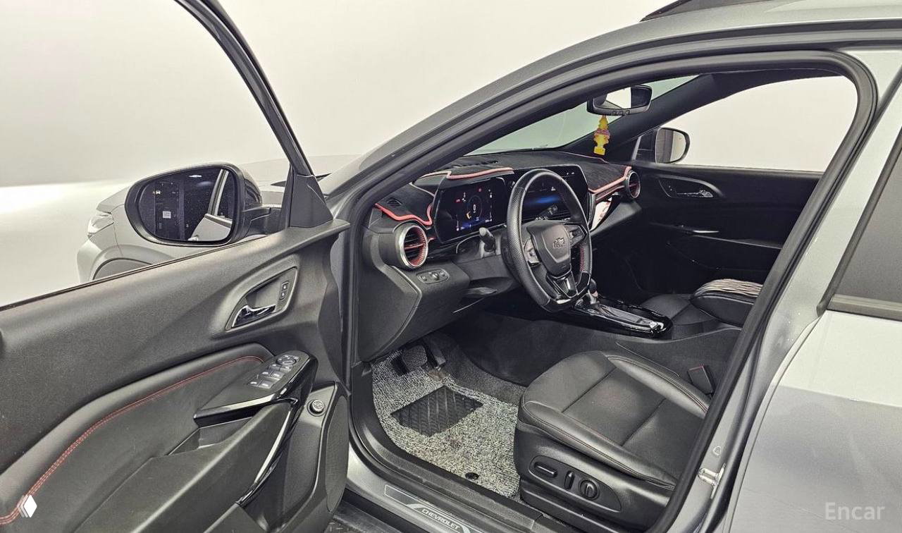Вид на переднее пассажирское пространство и водительскую дверь Chevrolet Trax RS: кресла из кожи, центральный тоннель и кнопки управления на двери.