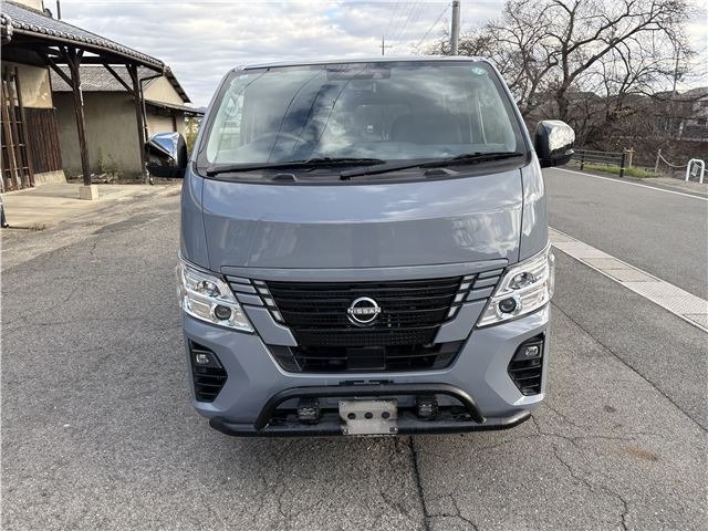 Фронтальный вид Nissan Caravan (2022) — крупный план решётки радиатора, бампера и фар, автомобиль на уличной парковке.