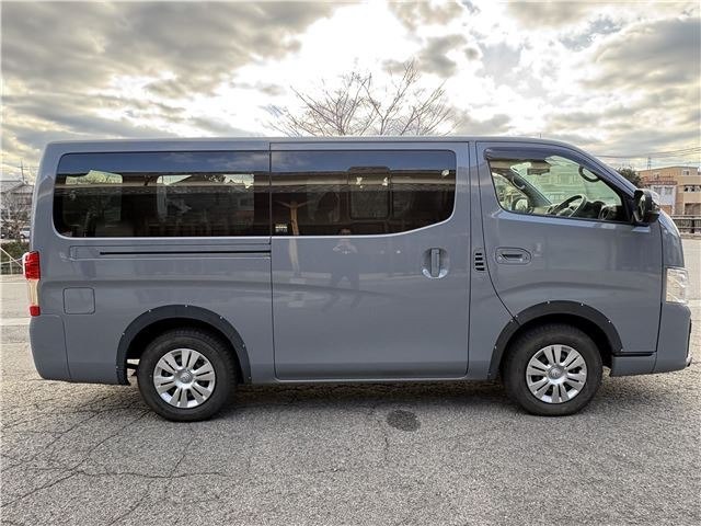 Вид справа Nissan Caravan 2022 — боковой ракурс с показом сдвижной двери и общего профиля микроавтобуса на фоне двора/улицы.