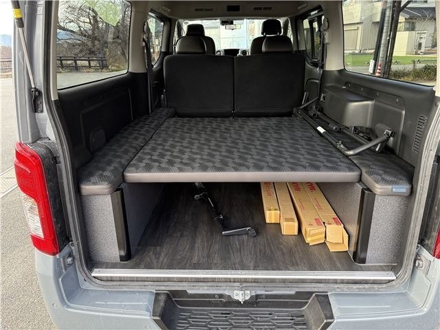 Грузовой отсек и спальное место в багажнике Nissan Caravan: вид из задней двери, показаны пол, полки и планировка для перевозки вещей.