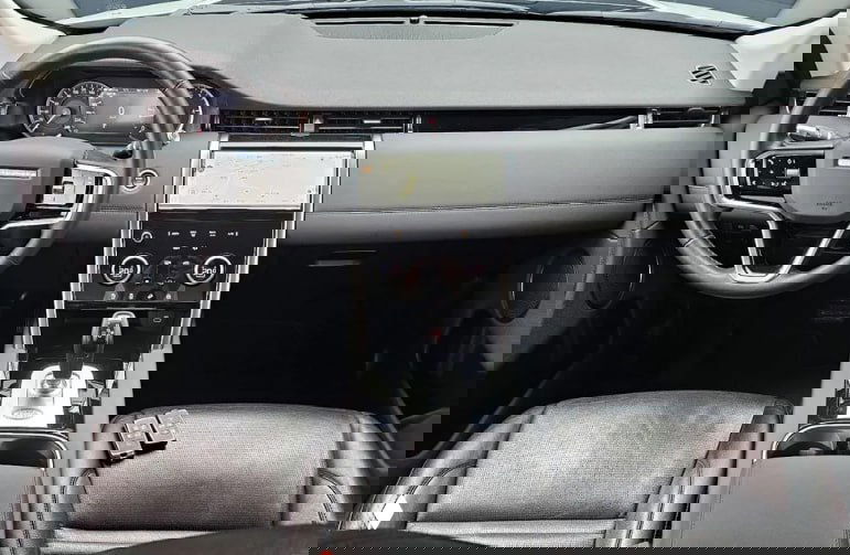 Интерьер Land Rover Discovery Sport: руль, торпедо и мультимедийная панель, передние кожаные сиденья — вид с водительской стороны.