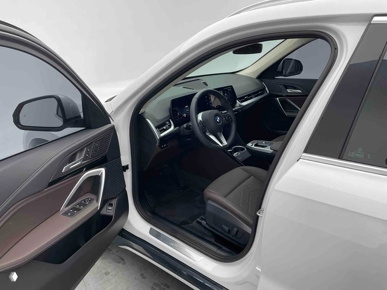 Открытая водительская дверь BMW X1, вид на кресло, дверную карту и элементы управления — демонстрируется состояние салона и отделки.