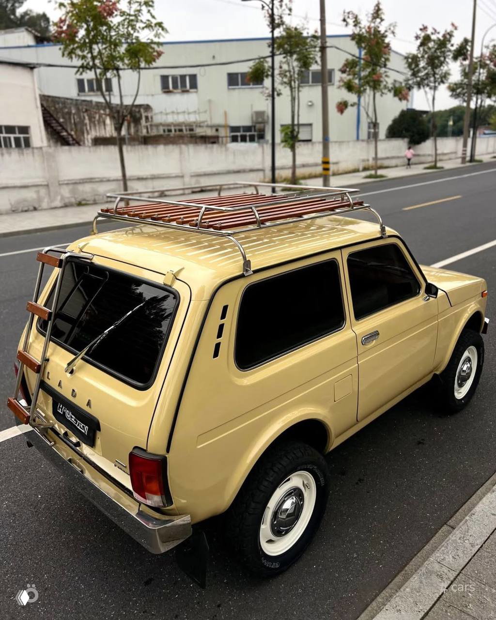 Виден верх и задняя часть светлой ретро‑Нивы с деревянными элементами багажника на крыше и аккуратной реставрацией кузова и хрома.