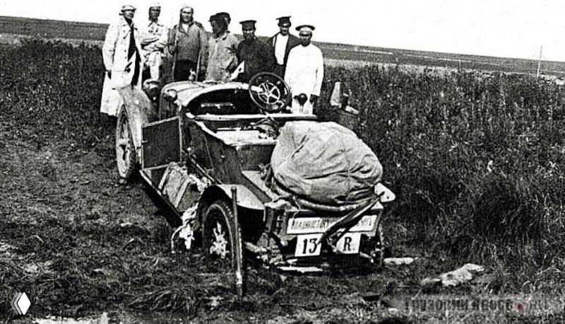 Ретро-автомобиль с поклажей на багажнике, экипаж и сопровождающие стоят на поле — снимок для фиксирования пути.