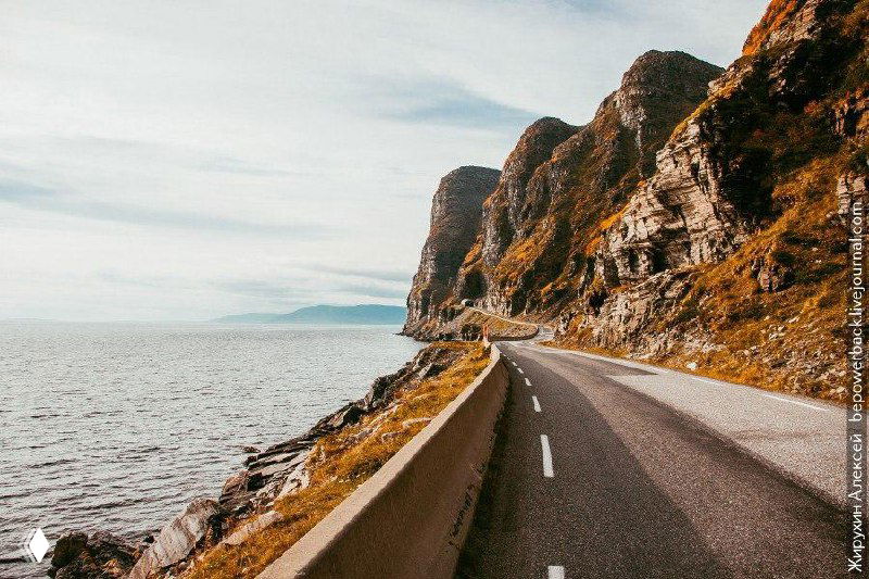 Прибрежная дорога вдоль моря с искаженными цветами и графическими артефактами — художественный или поврежденный снимок дороги у фьордов.