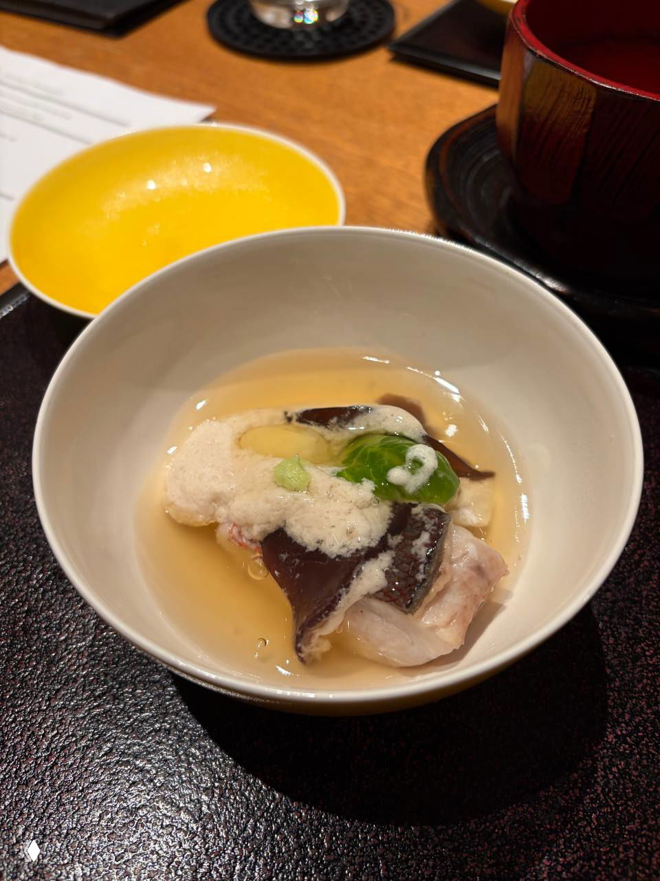 Небольшая пиала с желеобразной текстурой и кусочками морепродуктов, сверху белая воздушная пенка — авторская подача в кулинарном стиле кёдзю.