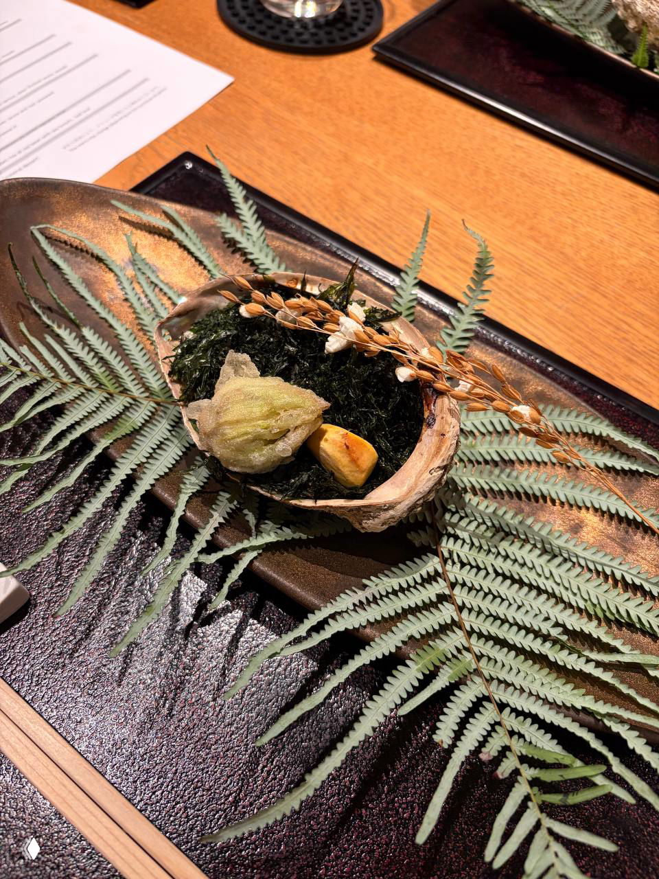 Миниатюрный декоративный сервиз с морскими элементами: ракушка, водоросли и жареные зерна — эстетическая презентация морепродуктов.