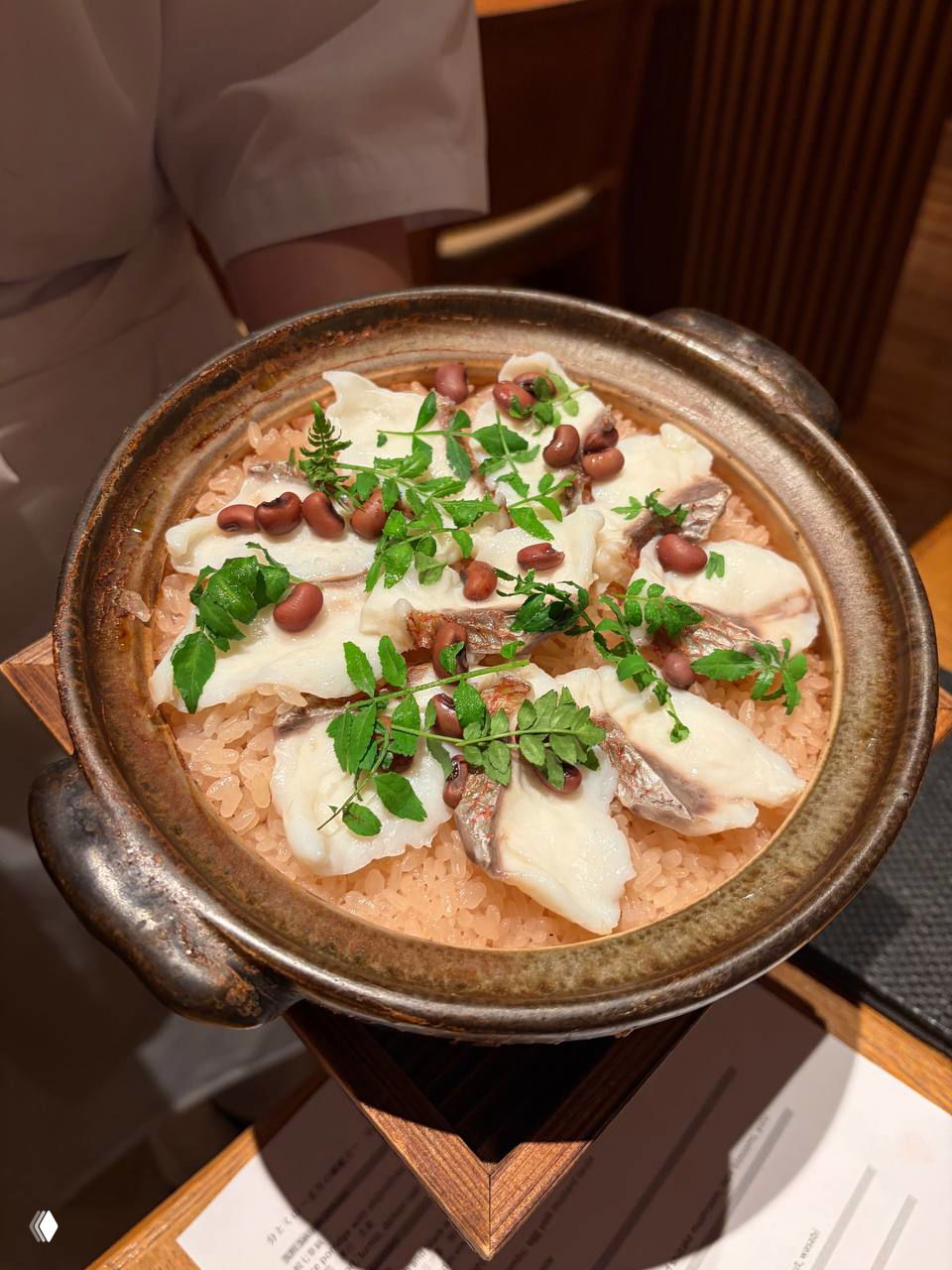 Горшочек с рисом и кусочками белой рыбы сверху, украшенный зеленью и бобами — основное горячее блюдо из сет-меню.