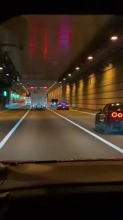 Тёмно‑синий Nissan GT‑R с наклейкой 'GAIJIN TUNED' на задней части, агрессивный обвес и широкие арки колёс, съемка ночью среди других автоэнтузиастов.