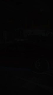 Низкий ракурс колеса гоночного автомобиля с маркировкой Dunlop и крупной шиной; оранжево‑жёлтое вечернее освещение подчёркивает фактуру покрытия.