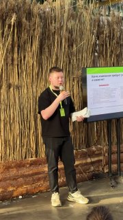 Докладчик на сцене выставки Hello Camper — спикер команды ТЕСТ‑ДРАЙВ рассказывает про тюнинг и строительство автодомов на фоне презентации и декора.