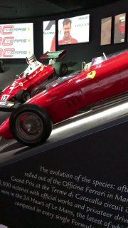 Выставка исторических гонок и экспонатов Ferrari: стенды с информацией и образцы старых гоночных автомобилей и экспонатов.