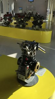 Ряд двигателей и технических узлов на желтых постаментах в отдельном зале музея, демонстрация механики и инженерной части Ferrari.