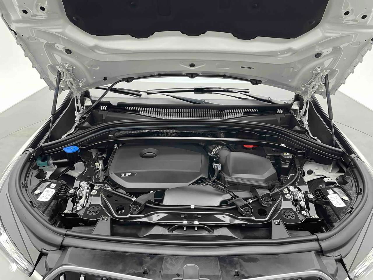 Фото моторного отсека BMW X1 с открытым капотом, видна накладка двигателя и элементы шасси, состояние чистое, без следов течи.