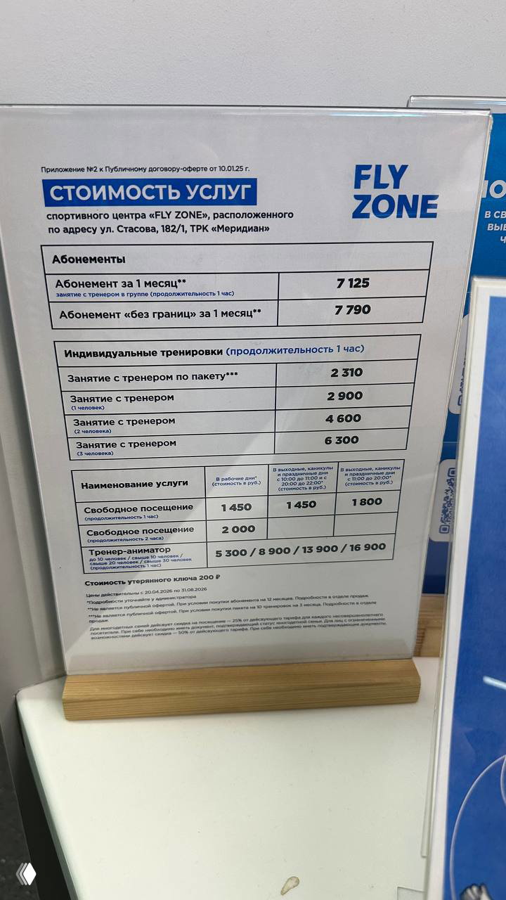 Табличка со стоимостью услуг батутного центра Fly Zone: абонементы, индивидуальные тренировки и цены на свободное посещение указаны на стойке ресепшен.