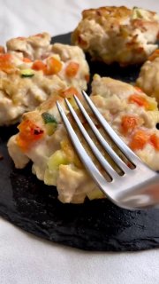 Крупный план рубленых куриных ПП-котлет с видимыми кусочками моркови и кабачка на тёмной подставке, рядом металлическая вилка