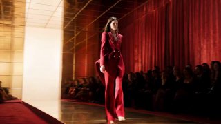 Модель в красном костюме шагает по подиуму Парижской недели моды; зрители в тёмной зале, показ Алексиса Мабия с пиксельными эффектами.
