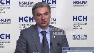 Депутат в костюме говорит у микрофона на пресс‑конференции, за ним видны баннеры с логотипами НСН и надписью Национальная служба новостей.