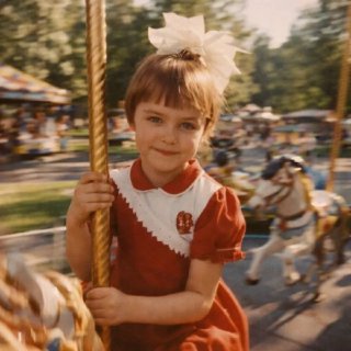 Ребёнок на карусели в парке при тёплом солнечном свете; размытие фона, эффект движения и ностальгическая домашняя эстетика фотографии.