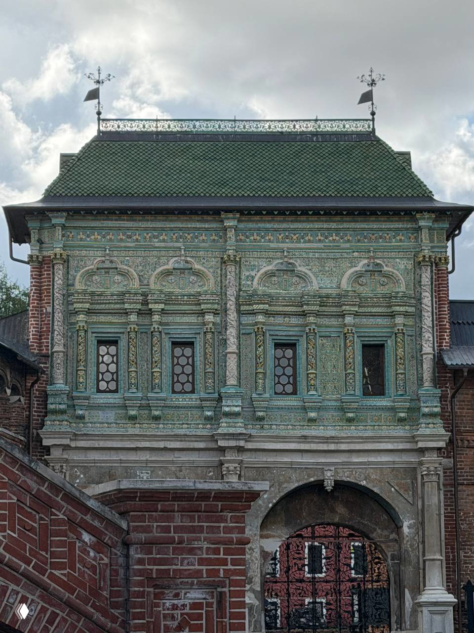 Детальная роспись и изразцы Крутицкого теремка: зелёная полихромная отделка второго яруса над аркой входа с орнаментом и резьбой