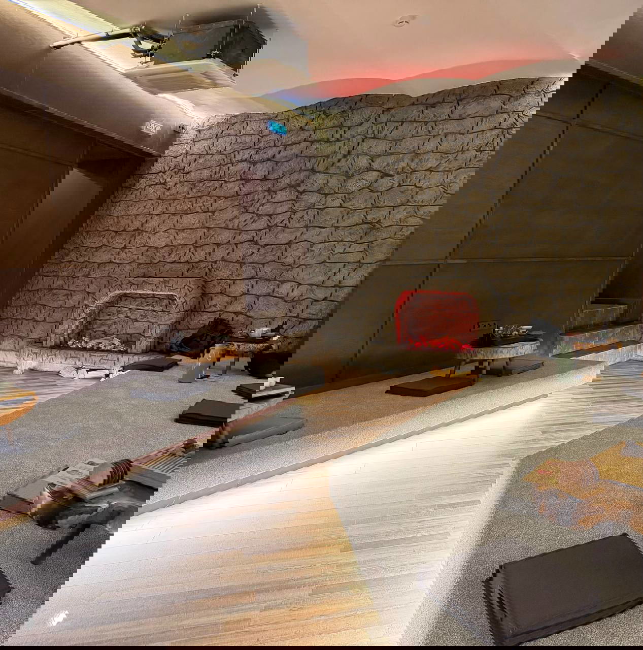 Угловая часть зала с имитацией каменной стены и подсвеченным «камином», поднятые платформы с подушками и маленькими столиками для спокойного чаепития.