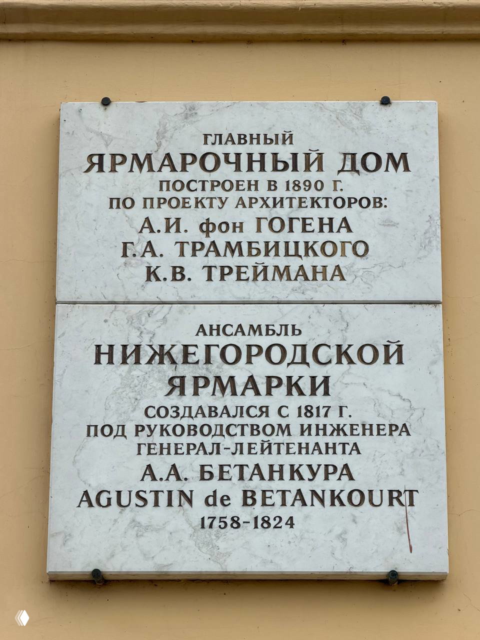 Каменная мемориальная доска у входа в Главный ярмарочный дом с надписью о постройке 1890 года и упоминанием архитекторов и Бетанкура.