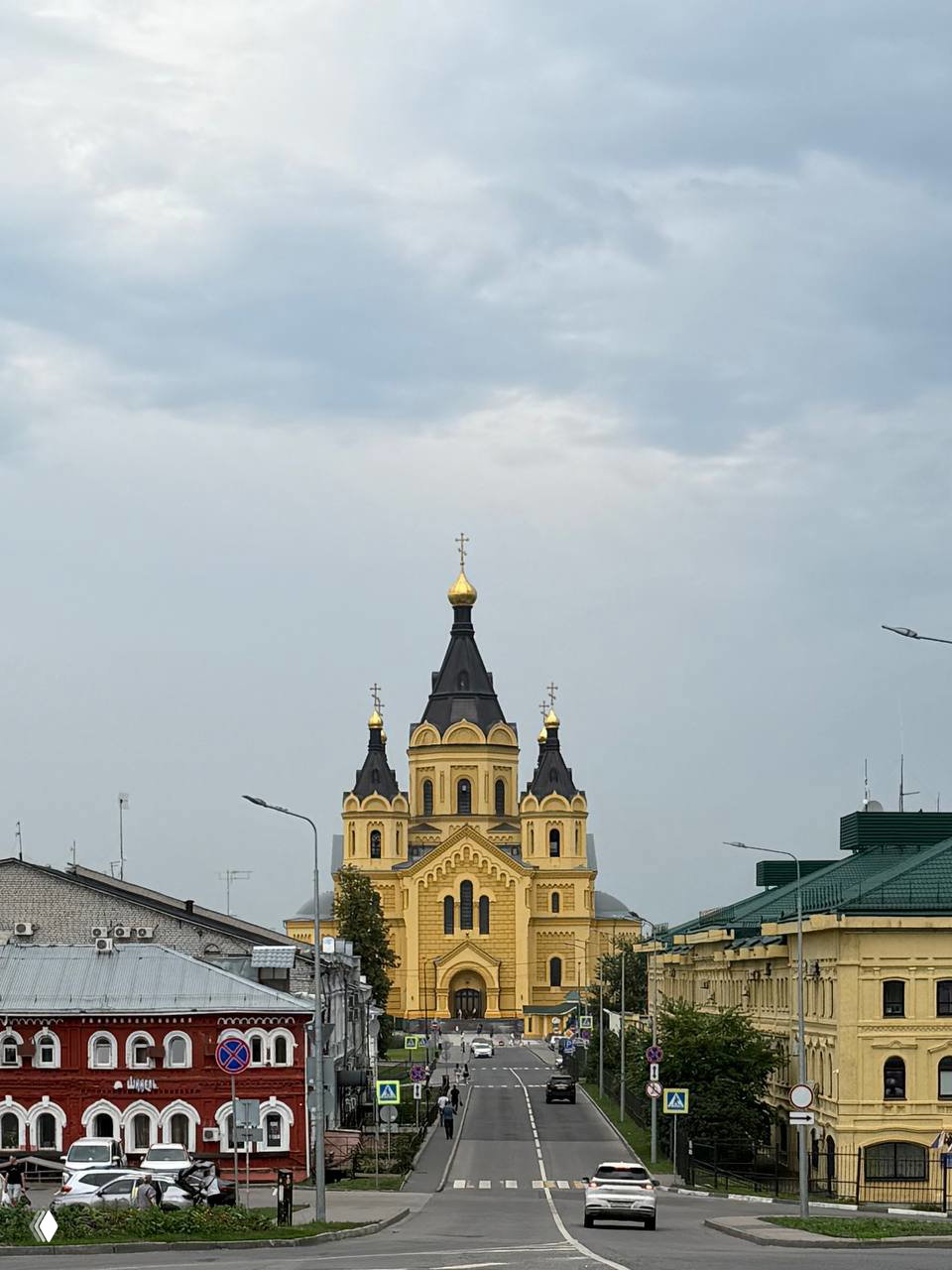 Вид на Александро-Невский собор в Нижнем Новгороде с улицы: золотые купола, неоклассический фасад и городской пейзаж перед ним.