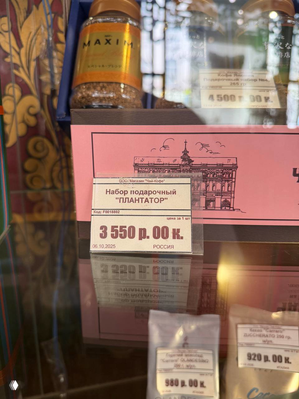 Ценник подарочного набора «Плантатор» в витрине чайного магазина на фоне оформления, отражений в стекле и других товаров