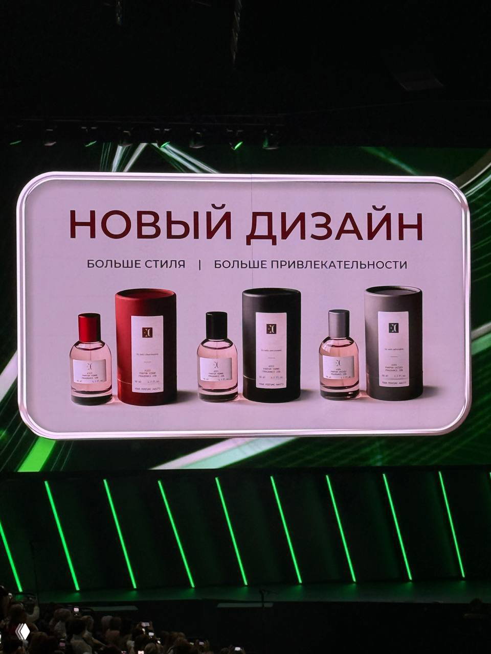 Слайд с надписью «НОВЫЙ ДИЗАЙН»: ряд флаконов и цилиндрических упаковок Enjoy Care на белом фоне, презентация на сцене перед публикой.