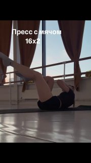 Женщина в студии выполняет упражнение на пресс с фитнес‑мячом на полу; на фото видна надпись «Пресс с мячом 16x2».