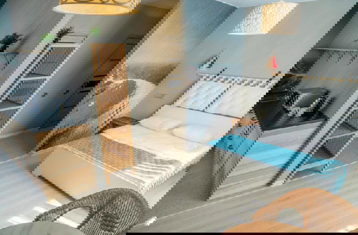 Кухонная зона и гостиная с деревянной мебелью, стеклянным шкафом для напитков и декоративными подвесными светильниками.