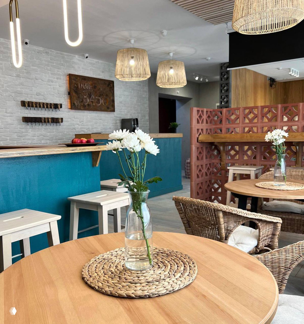 Ресепшен и зона столиков с плетёной мебелью, вазами с цветами и тёплыми натуральными материалами в интерьере.
