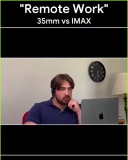 Мужчина за ноутбуком дома, имитирующий мем «IMAX у удалёнщиков»: созвон и задумчивый взгляд на фоне часов и лампы в комнате